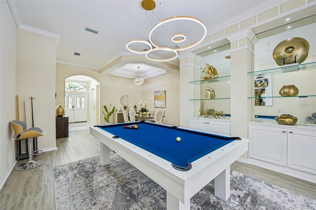 A game room features a white pool table, modern circular lighting, and built-in display shelving — 7760 US OPEN LOOP, LAKEWOOD RANCH, FL