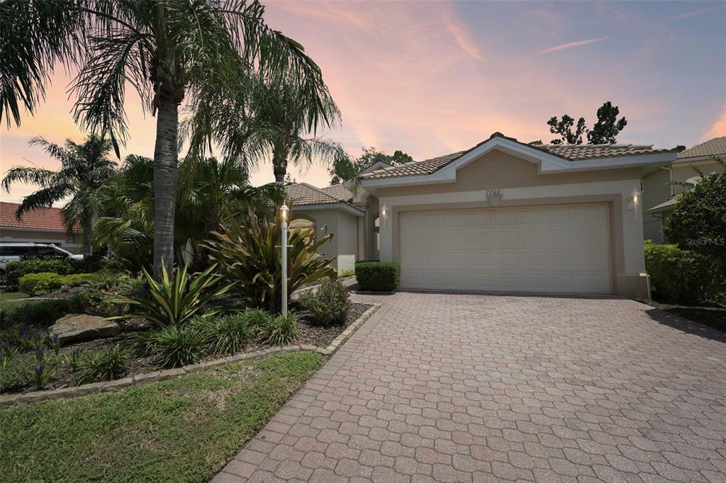 A single-story house with a beige exterior, a two-car garage, and a paved driveway — 7760 US OPEN LOOP, LAKEWOOD RANCH, FL
