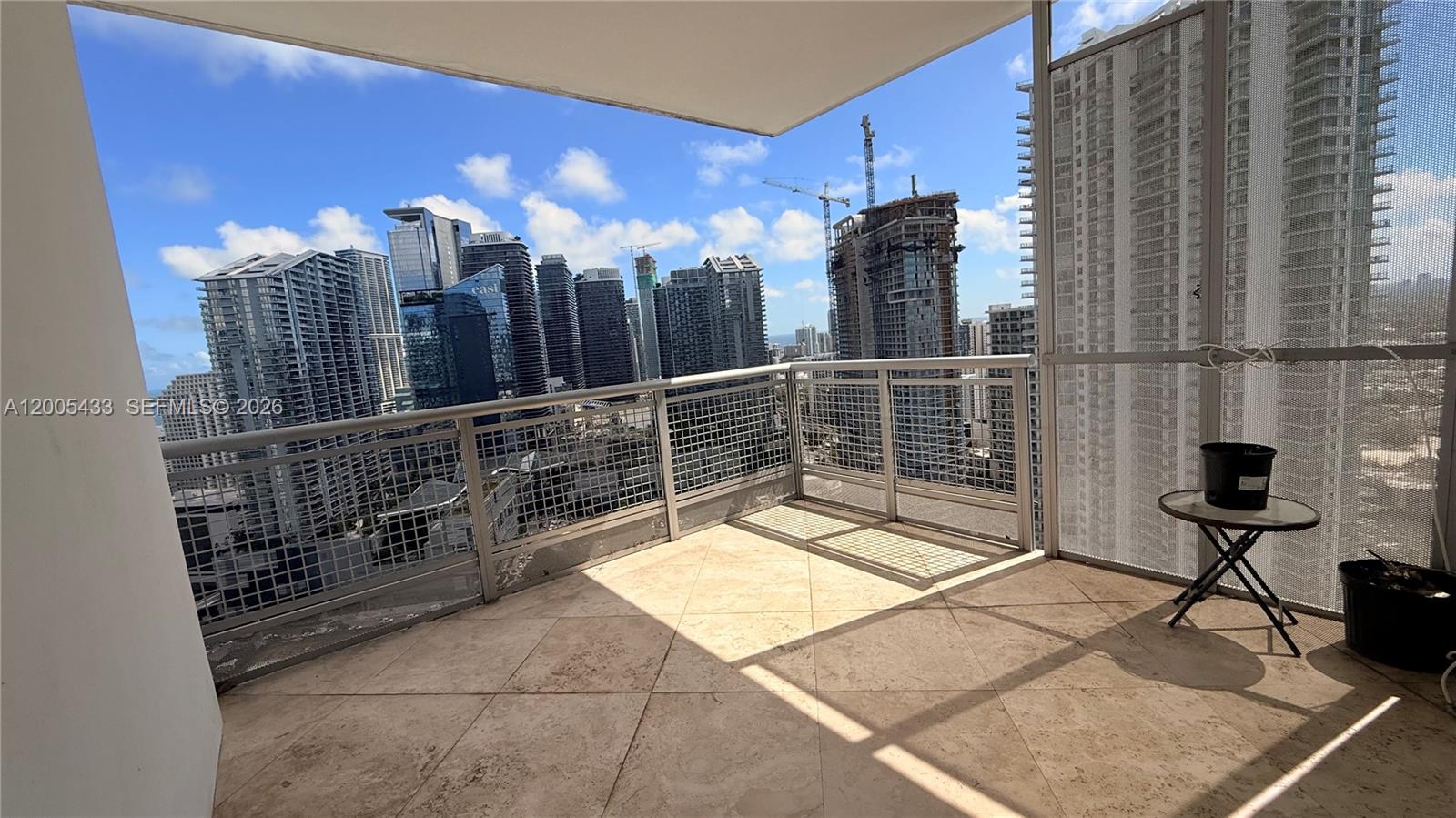 A balcony with tile flooring overlooks a dense city skyline under a blue sky — 350 S Miami Ave # 3608, Miami FL 33130, MIAMI, FL