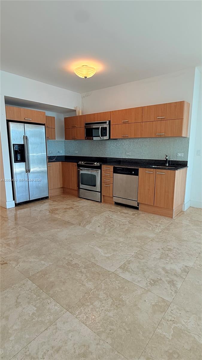 A kitchen features light wood cabinets, stainless steel appliances, dark countertops, and beige tile flooring — 350 S Miami Ave # 3608, Miami FL 33130, MIAMI, FL