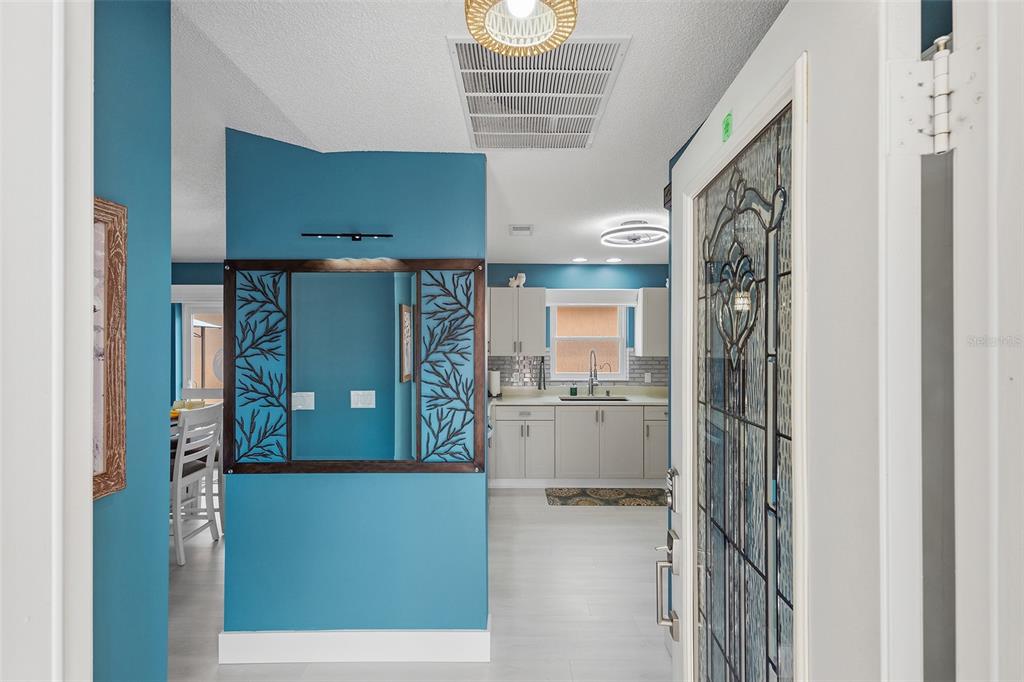 An entryway with blue walls leads to a kitchen and a dining area — 868 OVIEDO ROAD, THE VILLAGES, FL
