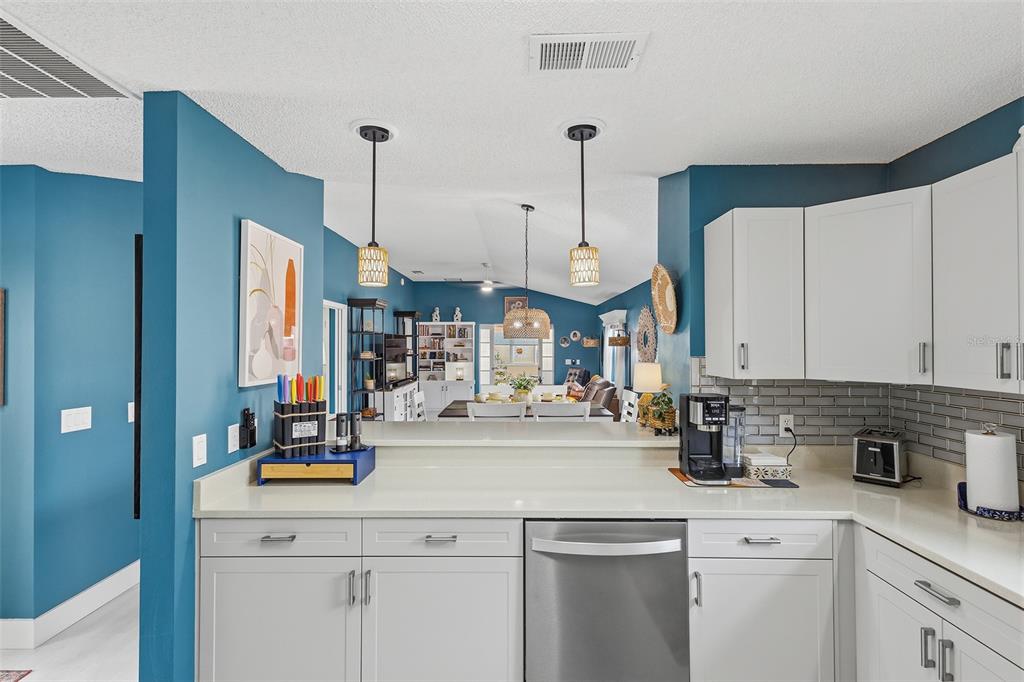 A kitchen with white cabinets and stainless steel appliances overlooks a blue-walled dining area — 868 OVIEDO ROAD, THE VILLAGES, FL