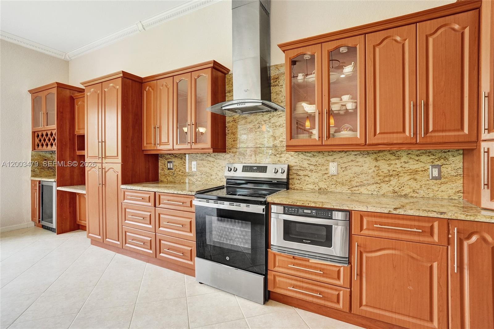 A kitchen features wood cabinets, granite countertops, stainless steel appliances, and a tile floor — 1169 Peregrine Way, Weston FL 33327, WESTON, FL