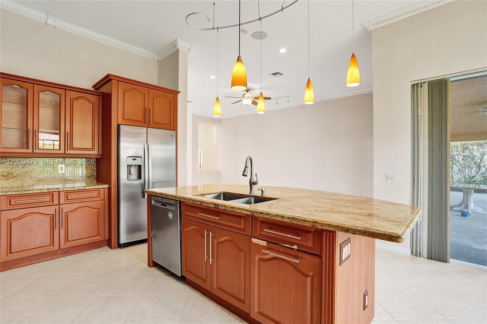 A kitchen features wood cabinetry, granite countertops, a central island, and stainless steel appliances — 1169 Peregrine Way, Weston FL 33327, WESTON, FL