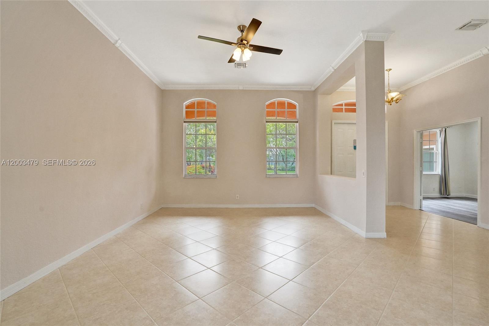 An empty room features beige tile flooring, two arched windows, and a ceiling fan — 1169 Peregrine Way, Weston FL 33327, WESTON, FL