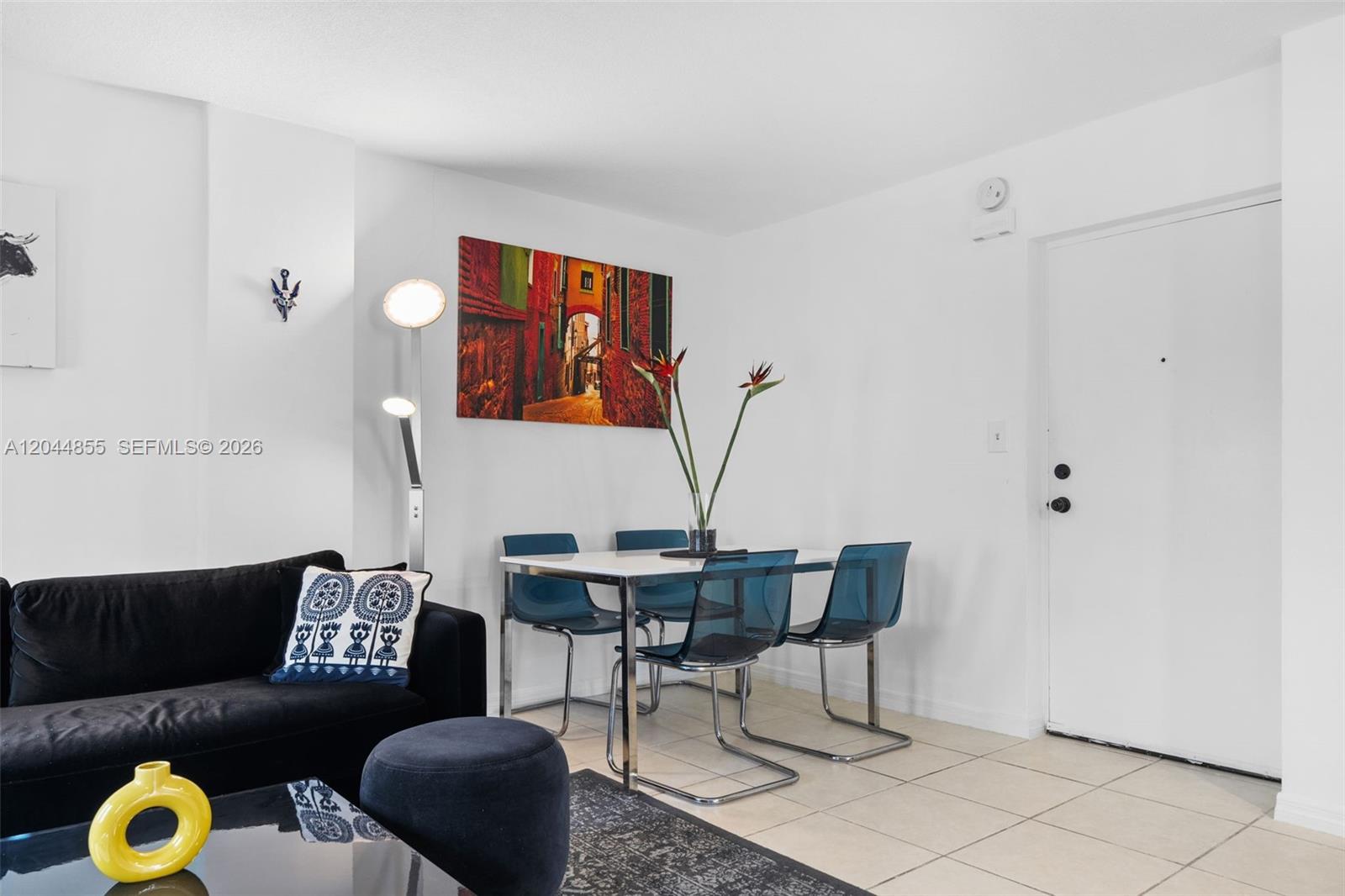 A living and dining area features a black sofa, blue chairs, and tile flooring — 801 S Ocean Dr # 207, Hollywood FL 33019, HOLLYWOOD, FL