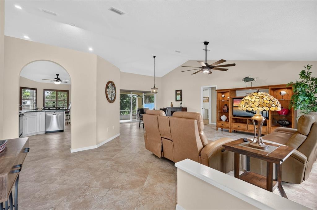 A living room with tan tile flooring, leather recliners, and an arched entryway to the kitchen — 40 FLAMINGO DRIVE, PALM COAST, FL