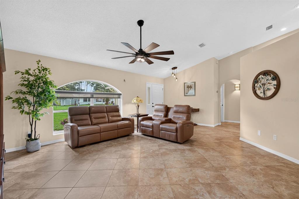 A living room with tan tile floors, two brown leather sofas, and a ceiling fan — 40 FLAMINGO DRIVE, PALM COAST, FL