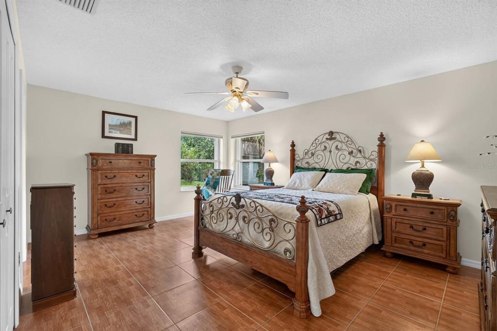 A bedroom features a wrought iron and wood bed, tile flooring, and a ceiling fan — 40 FLAMINGO DRIVE, PALM COAST, FL