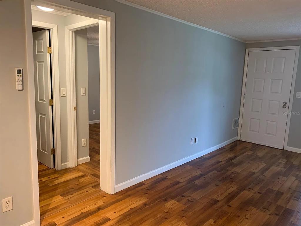An interior view shows a room with wood flooring, light gray walls, and two doorways — 4301 E MICHIGAN STREET UNIT 4301, ORLANDO, FL