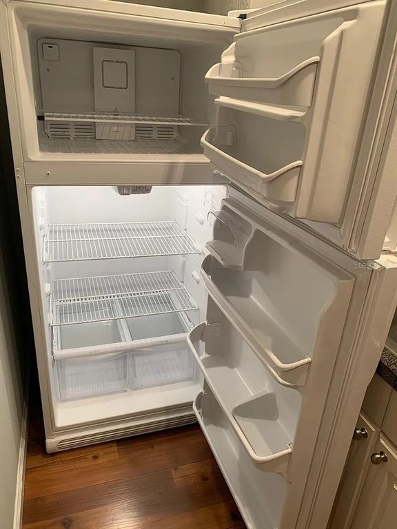 An open white top-freezer refrigerator stands in a kitchen with wooden flooring — 4301 E MICHIGAN STREET UNIT 4301, ORLANDO, FL