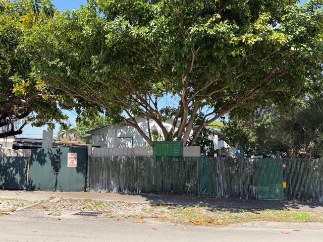 A large tree shades a house behind a green privacy fence and gate — 890 E 52nd St, Hialeah FL 33013, HIALEAH, FL