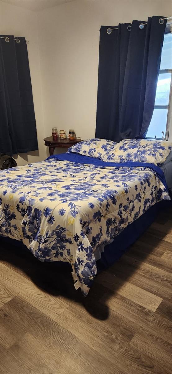 A bedroom features a bed with a blue and white floral comforter and dark curtains — 890 E 52nd St, Hialeah FL 33013, HIALEAH, FL