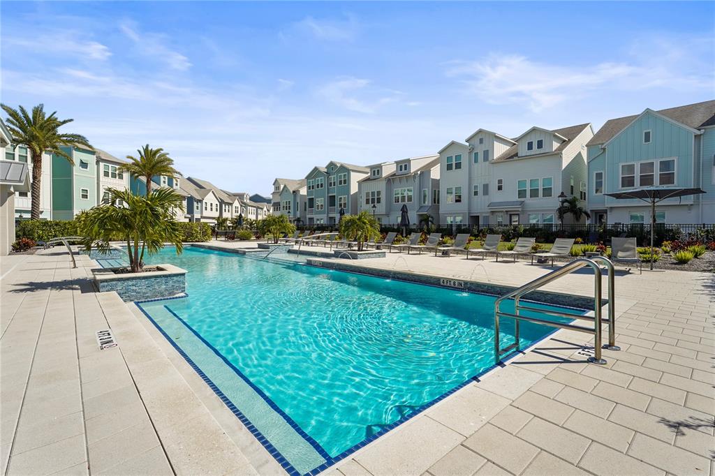 A rectangular swimming pool with lounge chairs and multi-story townhomes in the background — 2505 BOONE COURT, SARASOTA, FL
