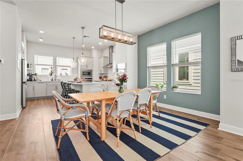 A dining area with a wooden table, patterned chairs, and a striped rug near a kitchen — 2505 BOONE COURT, SARASOTA, FL