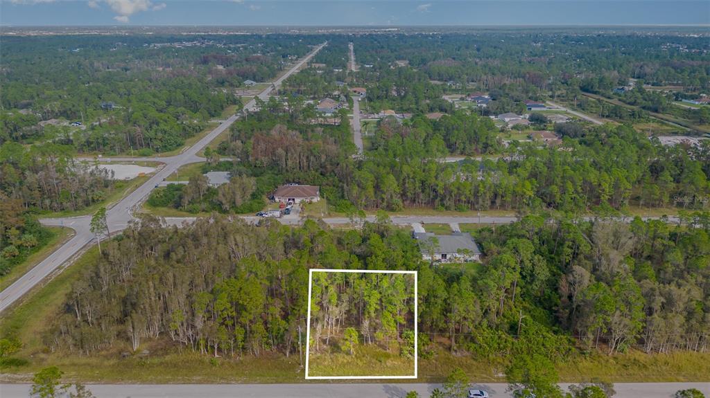 An aerial view shows a rectangular, wooded vacant lot outlined in white along a road — 609-611 LADD STREET, LEHIGH ACRES, FL