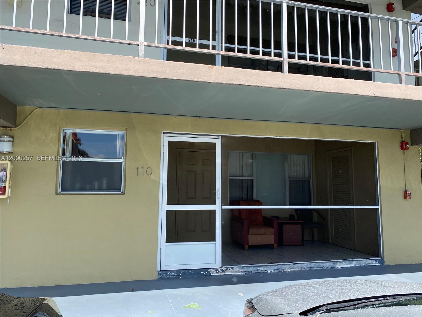A galley kitchen features light wood cabinets, white appliances, and a stainless steel sink — 250 Layne Blvd # 110, Hallandale Beach FL 33009, HALLANDALE BEACH, FL