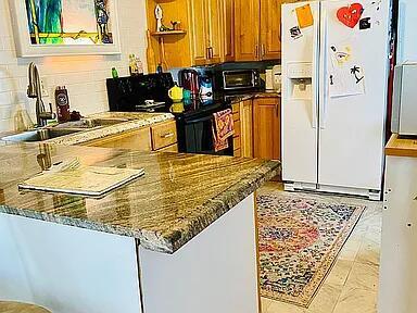 A kitchen features granite countertops, wood cabinets, a white refrigerator, and a patterned area rug — 1361 Overseas Highway # G5, Marathon FL 33050, MARATHON, FL