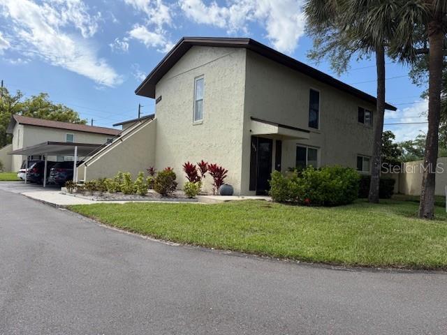 A two-story stucco apartment building features an exterior staircase and a covered parking area — 501 EAST BAY DRIVE UNIT 104, LARGO, FL