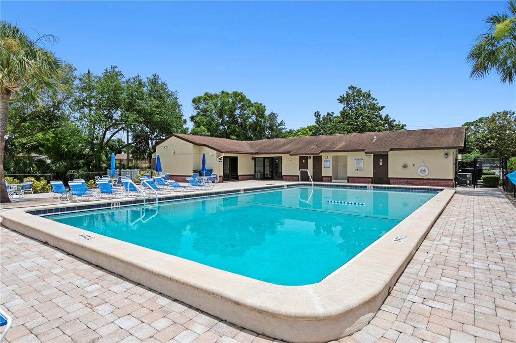 An outdoor swimming pool with lounge chairs on a paved deck next to a building — 501 EAST BAY DRIVE UNIT 104, LARGO, FL