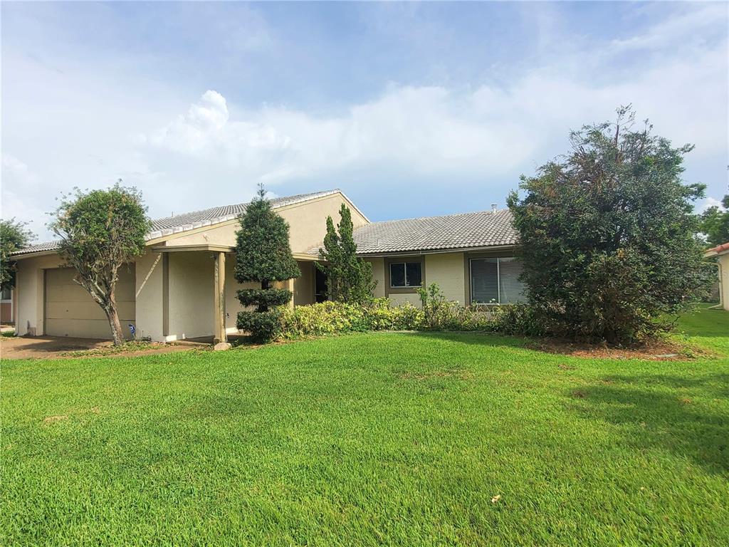 A single-story house with a beige stucco exterior, a tiled roof, and a large lawn — 5540 MINUTE MAN COURT, ORLANDO, FL