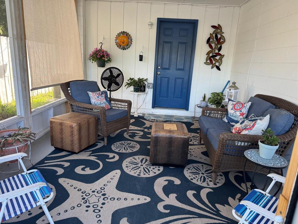 A screened-in porch features wicker furniture, a patterned area rug, and a blue door — 440 SW 264TH STREET, NEWBERRY, FL
