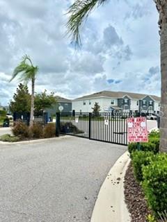 A gated entrance leads to a residential complex with multi-story buildings under a cloudy sky — 8771 FALLING BLUE PLACE, RIVERVIEW, FL