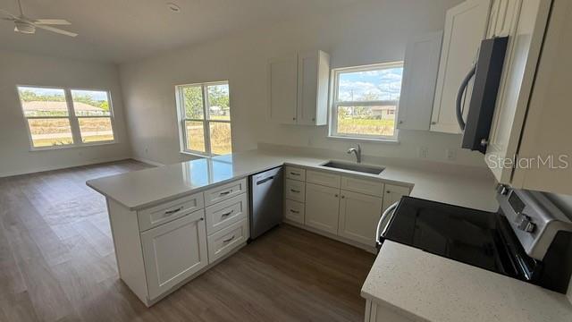 A modern kitchen features white cabinets, light countertops, stainless steel appliances, and wood-look flooring — 4123 MANDARIN ROAD, SEBRING, FL