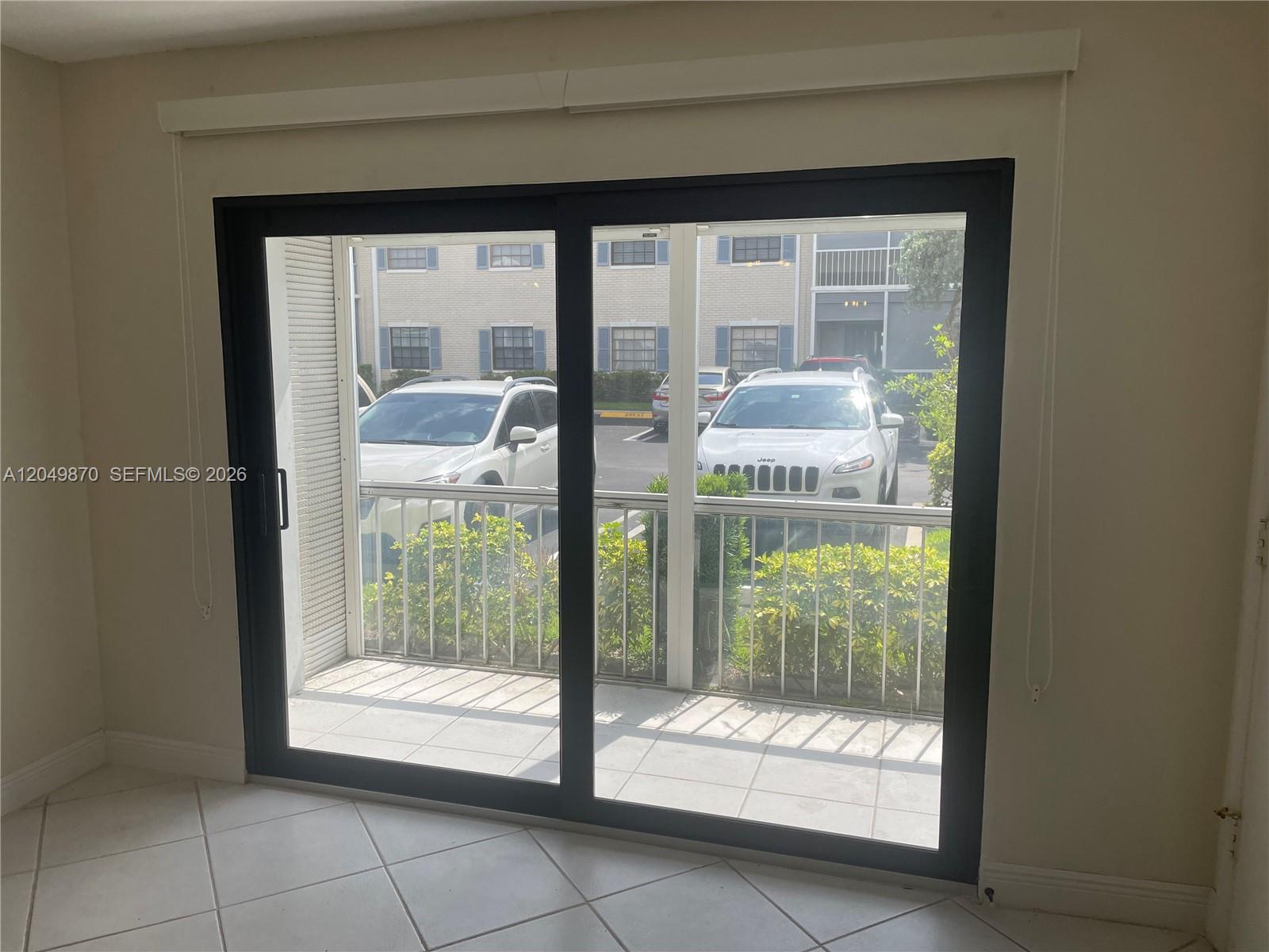 A view from inside a room through a sliding glass door onto a balcony — 110 Cypress Club Dr # 108, Pompano Beach FL 33060, POMPANO BEACH, FL