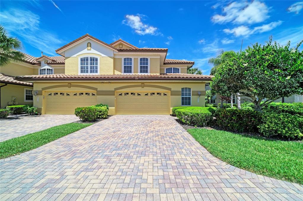 A two-story house with a paved driveway and a three-car garage under a clear sky — 8432 MIRAMAR WAY, LAKEWOOD RANCH, FL
