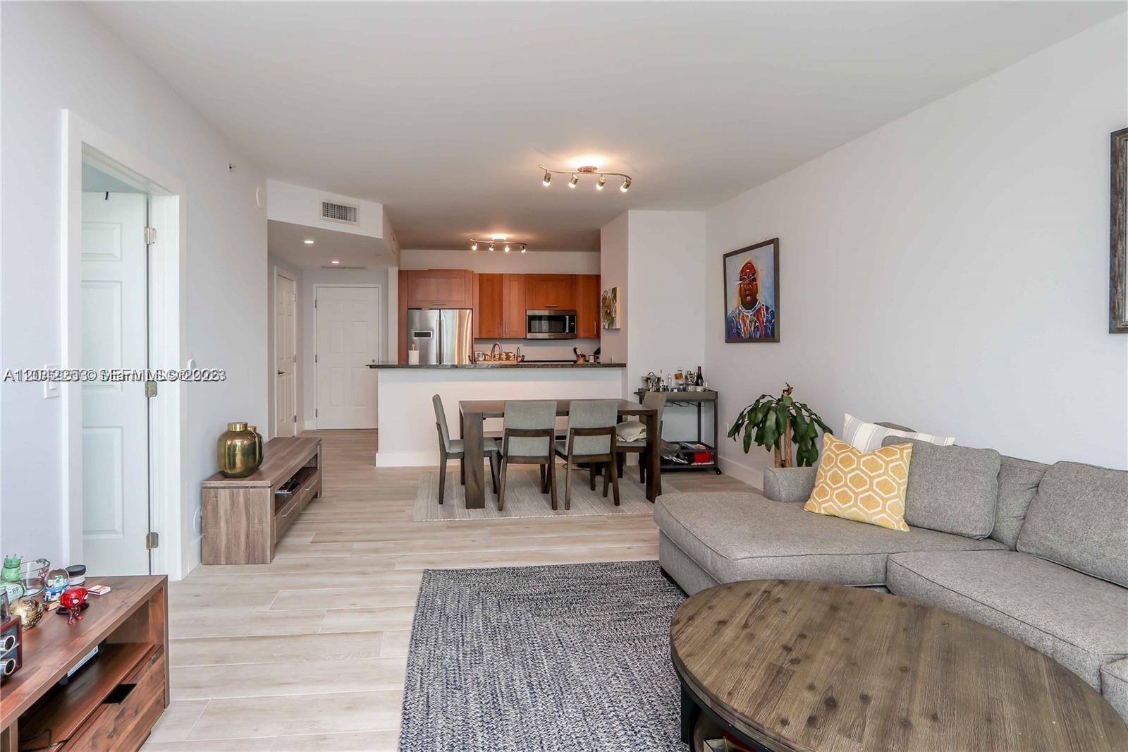An open-concept living and dining area features light wood flooring and a modern kitchen — 1300 Ponce De Leon Blvd # 500, Coral Gables FL 33134, CORAL GABLES, FL