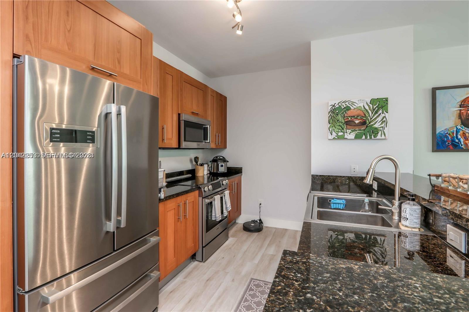 A kitchen features stainless steel appliances, wood cabinets, and dark granite countertops — 1300 Ponce De Leon Blvd # 500, Coral Gables FL 33134, CORAL GABLES, FL