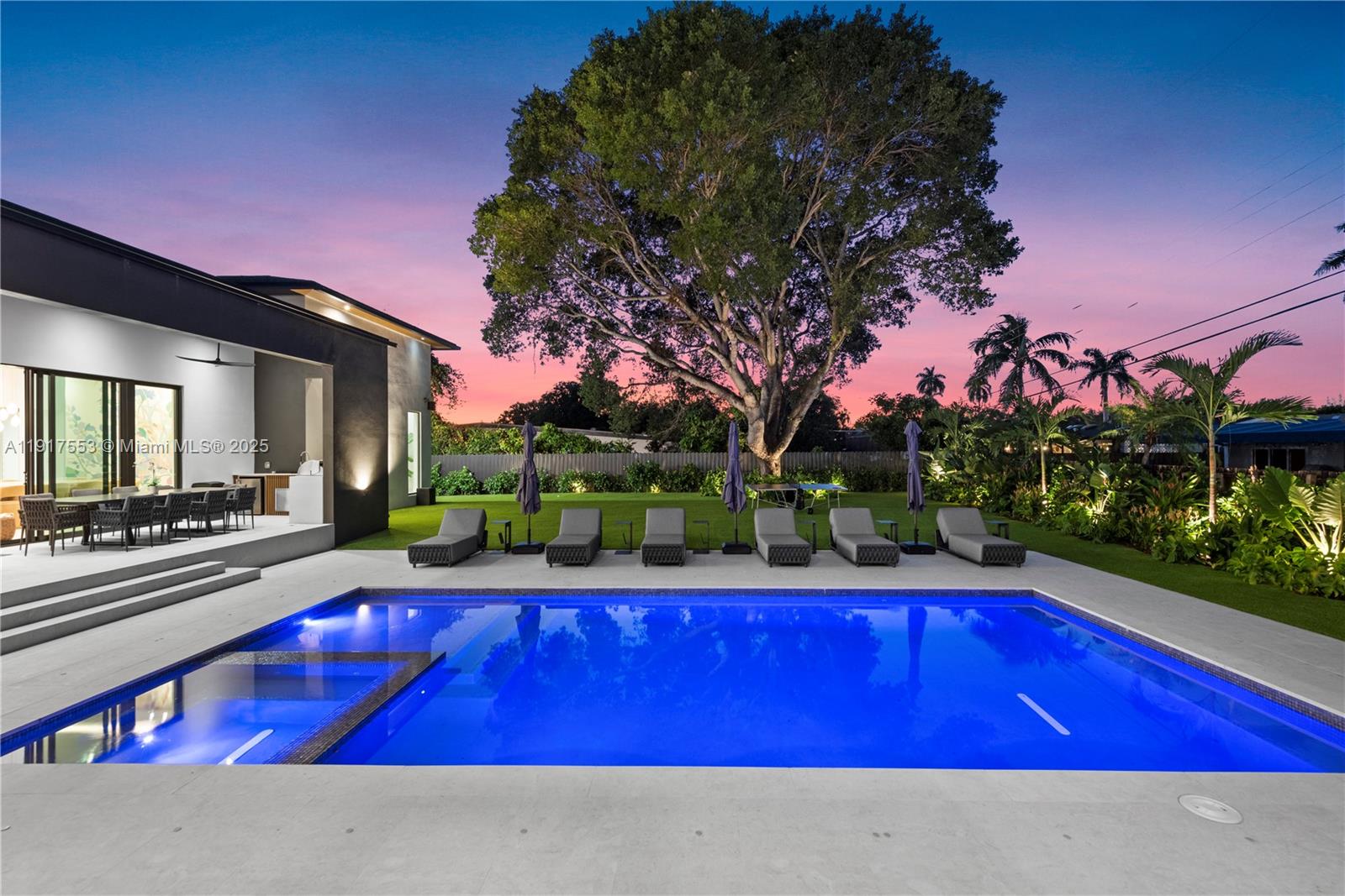 A modern house exterior features a swimming pool, lounge chairs, and a large tree — 1881 NE 196th Ter, Miami FL 33179, MIAMI, FL