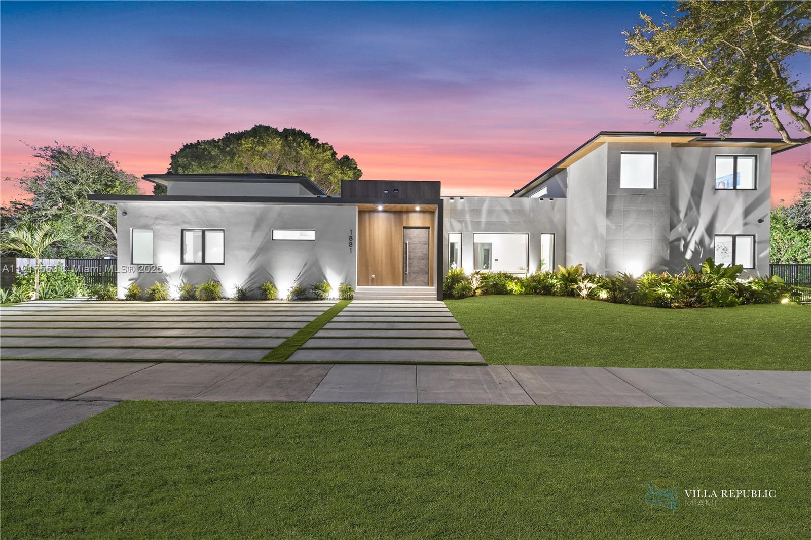 A modern two-story house features a concrete driveway, wood-paneled entryway, and landscaped front lawn — 1881 NE 196th Ter, Miami FL 33179, MIAMI, FL