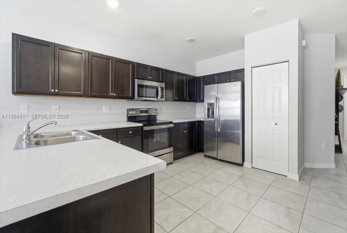 A kitchen features dark wood cabinets, stainless steel appliances, and white countertops — 11456 SW 252nd Ter, Homestead FL 33032, HOMESTEAD, FL