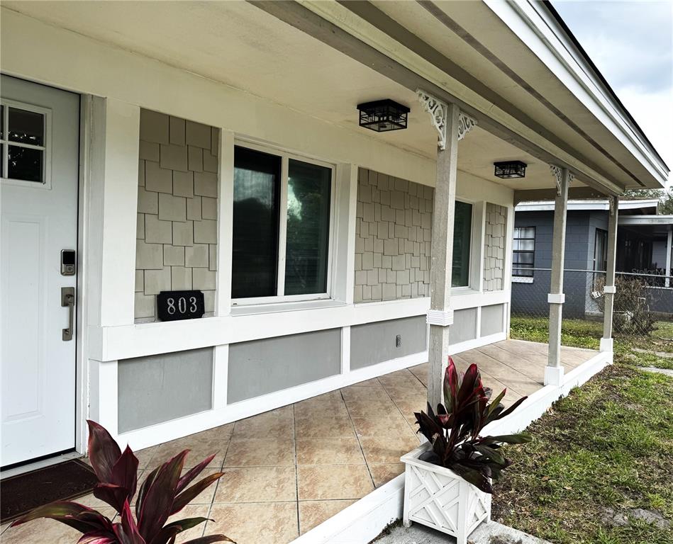 A covered front porch features tiled flooring, beige shingle siding, and white trim — 803 HASKELL AVENUE, ORLANDO, FL
