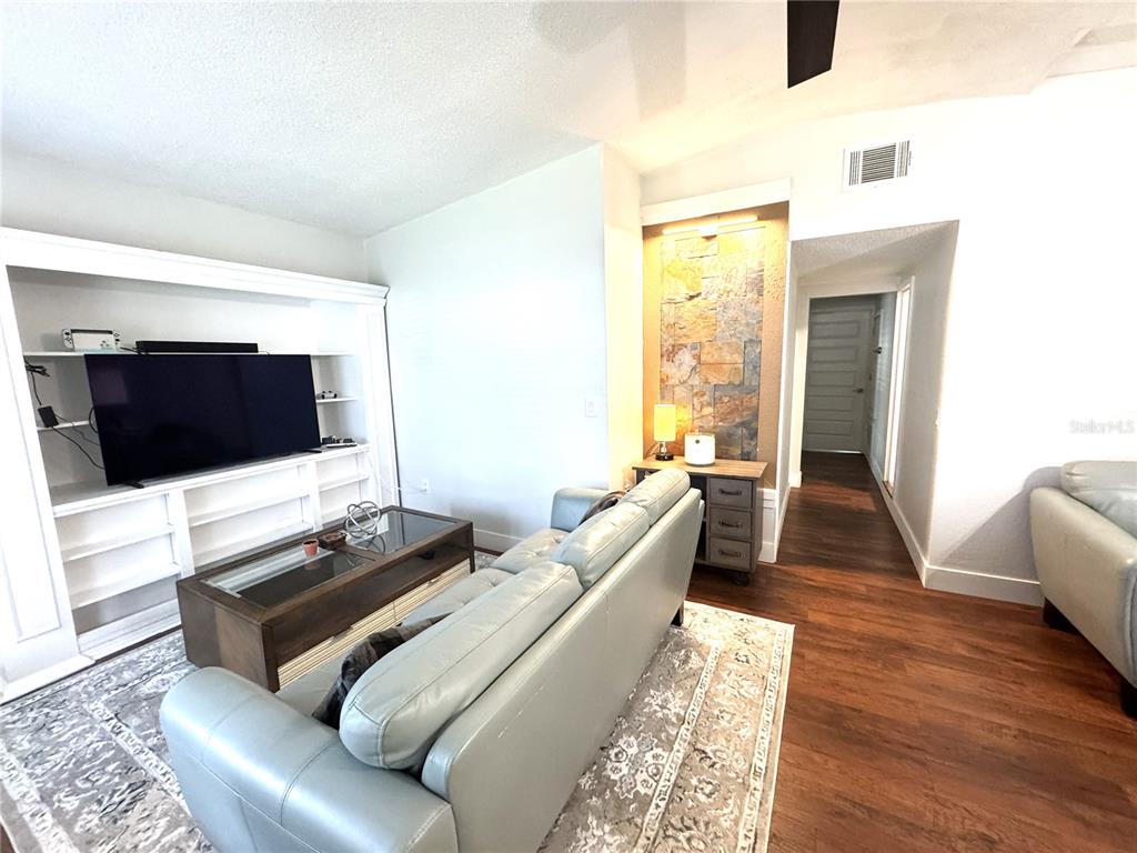 A living room features a large television unit, a light blue sofa, and a stone accent wall — 803 HASKELL AVENUE, ORLANDO, FL
