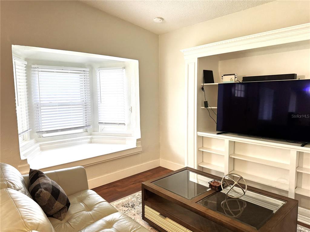A living room features a bay window, a white built-in media center, and a coffee table — 803 HASKELL AVENUE, ORLANDO, FL