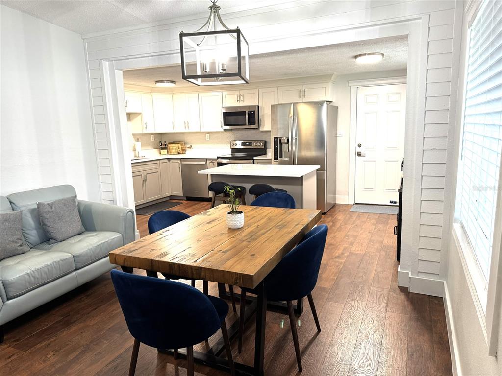 A dining area with a wooden table leads into a kitchen featuring stainless steel appliances — 803 HASKELL AVENUE, ORLANDO, FL