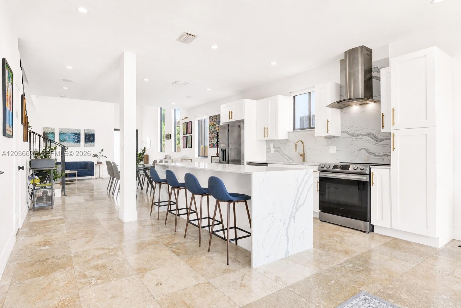 A modern kitchen features white cabinetry, a marble-topped island with blue stools, and tile flooring — 3022 SW 17th St # 3022, Miami FL 33145, MIAMI, FL