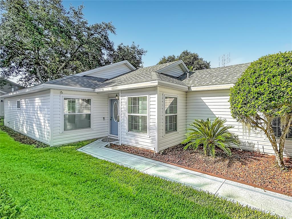 A white, single-story house with a concrete walkway leading to the front door — 25146 CRANES ROOST CIRCLE, LEESBURG, FL