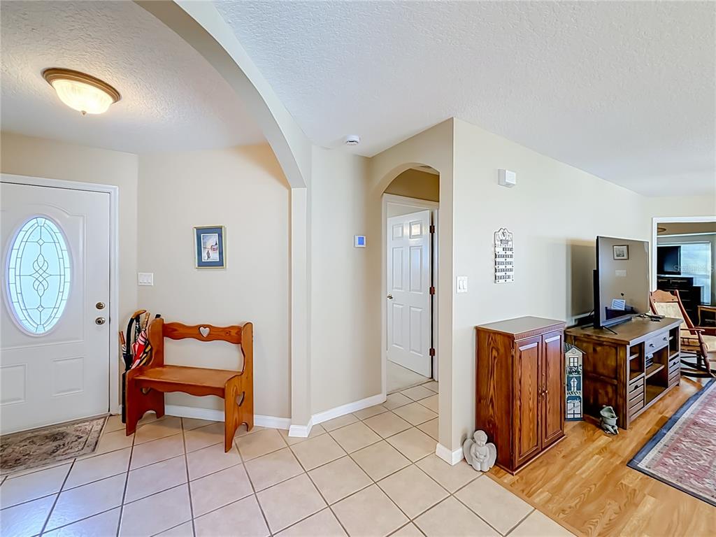 An entryway with tile flooring, a wooden bench, and an arched transition to a living area — 25146 CRANES ROOST CIRCLE, LEESBURG, FL
