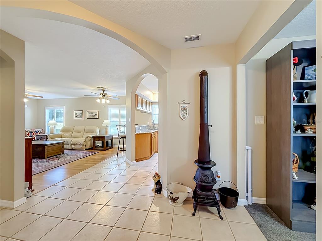 A tiled entryway leads to a living room and kitchen featuring an antique cast-iron stove — 25146 CRANES ROOST CIRCLE, LEESBURG, FL