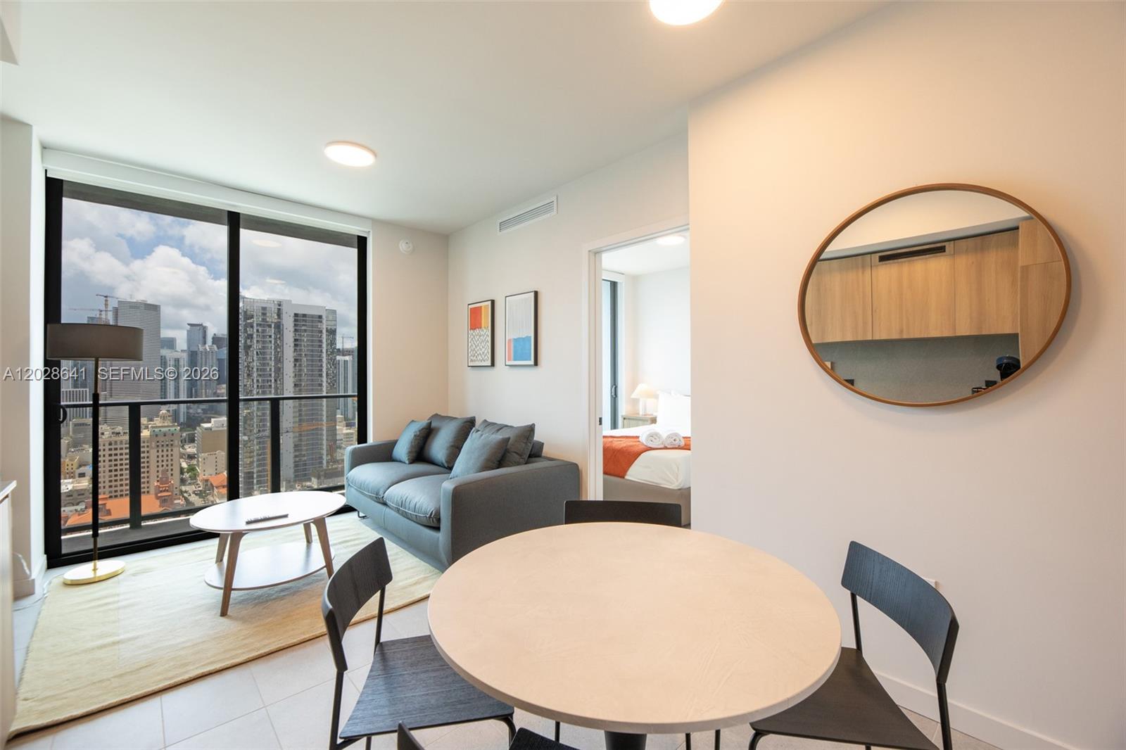A modern living and dining area features floor-to-ceiling windows overlooking a city skyline — 121 NE 5th St # 3103, Miami FL 33132, MIAMI, FL