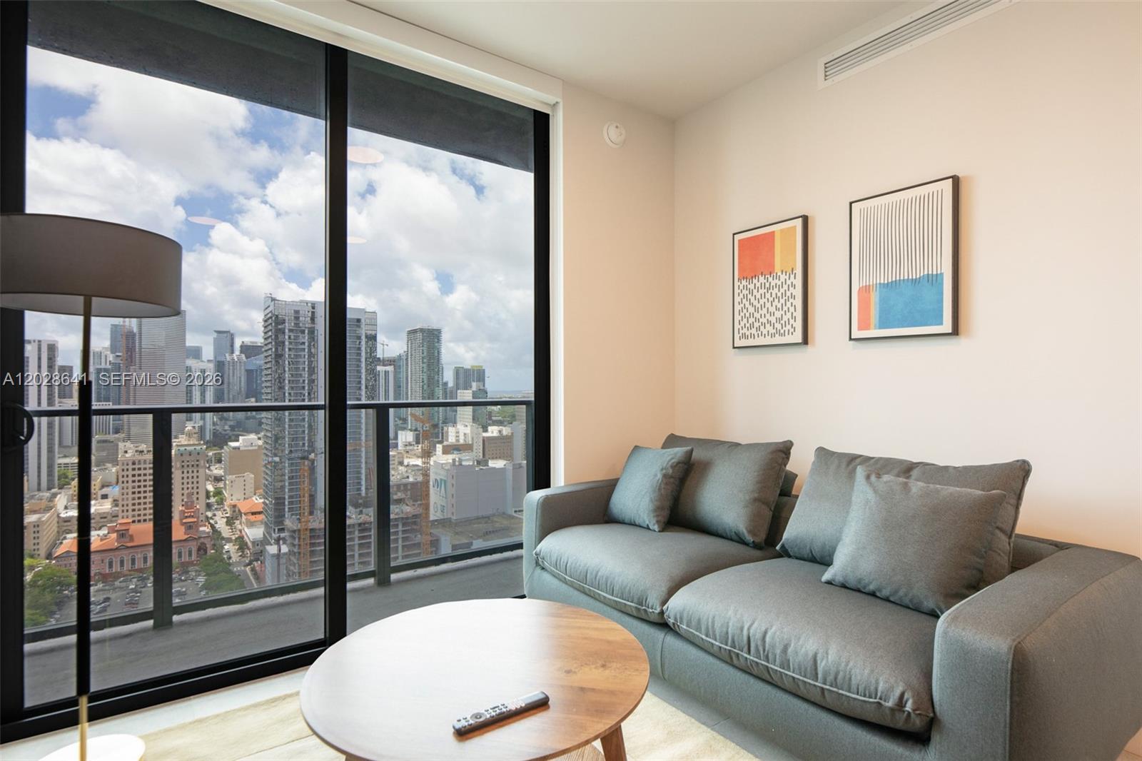 A living room features a grey sofa, a round wooden coffee table, and floor-to-ceiling windows — 121 NE 5th St # 3103, Miami FL 33132, MIAMI, FL