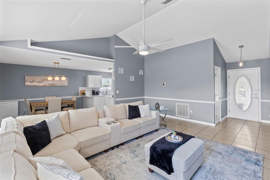 A living room features a large sectional sofa, vaulted ceilings, and an adjacent dining area — 122 CHURCH STREET S, LAKE HAMILTON, FL