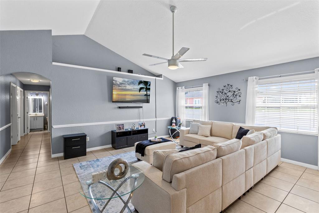 A living room features a vaulted ceiling, light gray walls, tile flooring, and a sectional sofa — 122 CHURCH STREET S, LAKE HAMILTON, FL