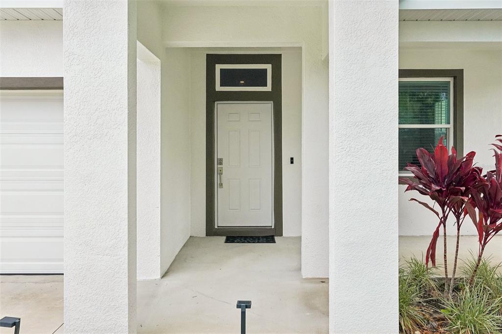 A covered entryway features a white front door with a transom window and stucco walls — 4277 43RD AVENUE N, ST PETERSBURG, FL