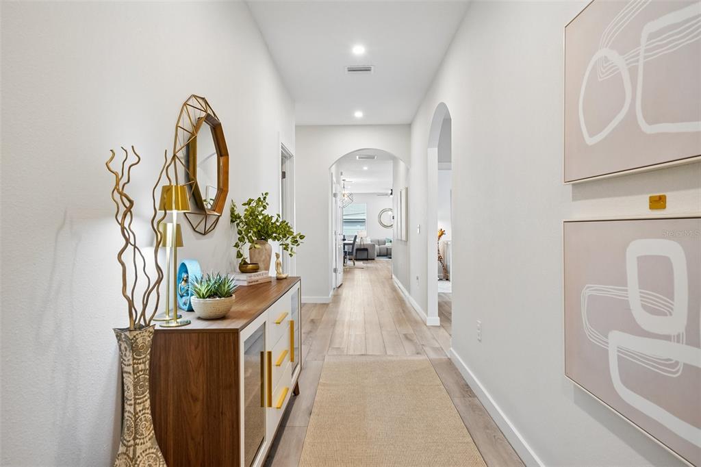 A hallway features light wood flooring, a wooden console table, and arched doorways — 4277 43RD AVENUE N, ST PETERSBURG, FL