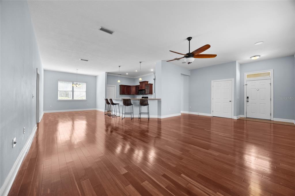 An open-concept living area features hardwood floors, a kitchen with a breakfast bar, and an entryway — 16609 NW 166TH DRIVE, ALACHUA, FL